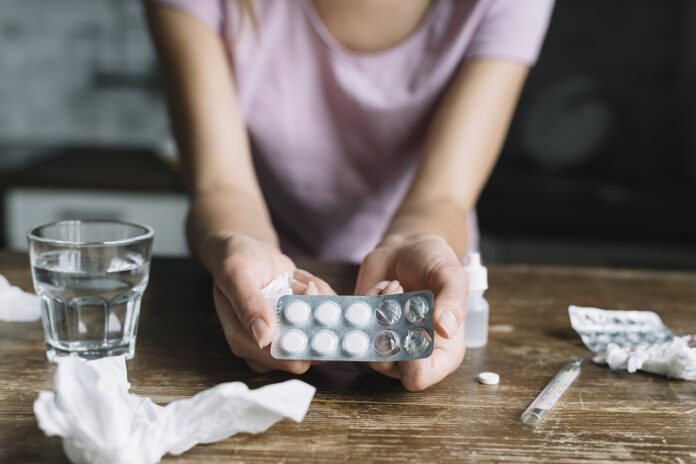 close-up-woman-s-hand-holding-blister-pack-with-medicines-wooden-deskss
