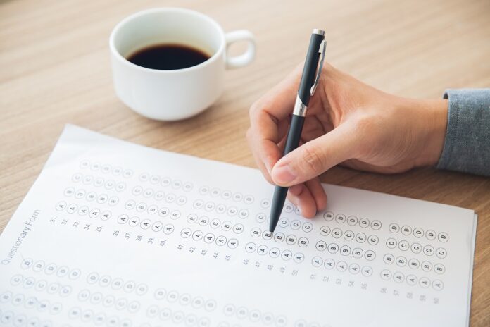 Male hand answering questionary form with pen